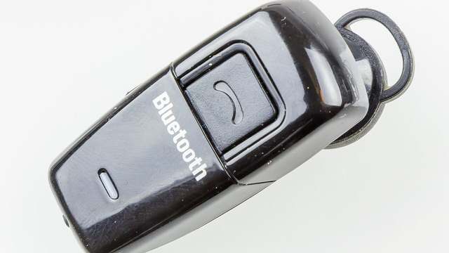 A small black mono Bluetooth headset with an ear hook