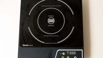 A white induction cooktop on a kitchen counter, a mains appliance
