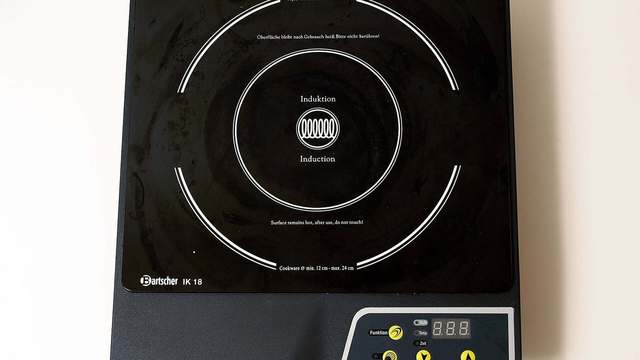 A white induction cooktop on a kitchen counter, a mains appliance