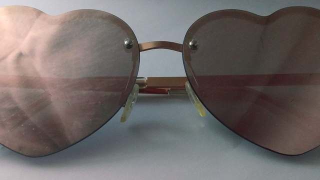 Heart-shaped sunglasses on a white background. Highway glare glasses are a darker, wraparound job than this pair