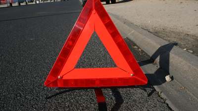 A red reflective warning triangle on the shoulder of a road