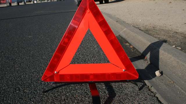 A red reflective warning triangle on the shoulder of a road